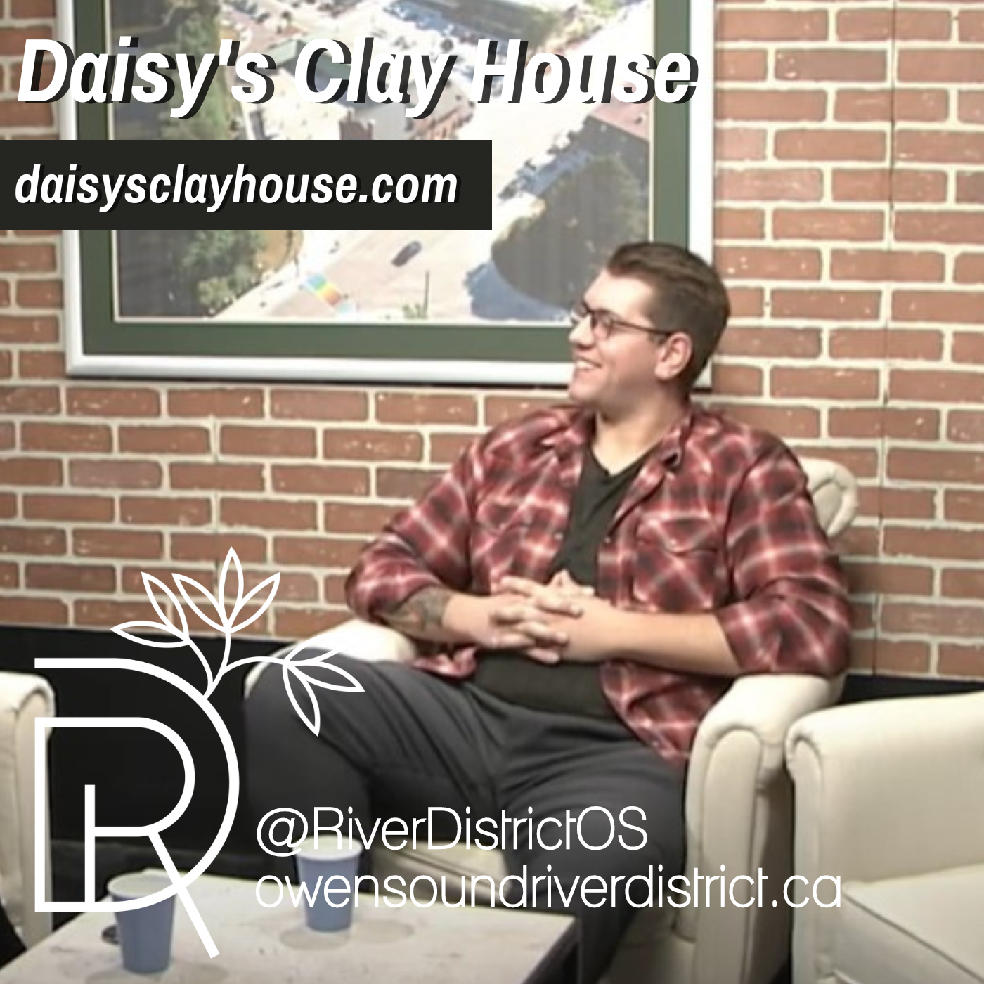 Evan Sansom in rogers studio with large picture frame and faux brick wall behind him